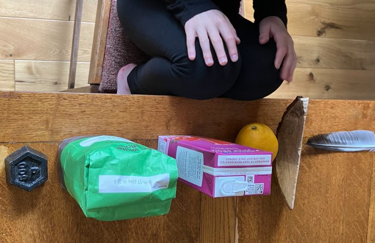 child in black sitting at a table with various items